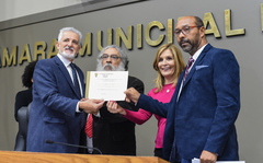 Movimentações no Plenário. Na foto, o vereador Engenheiro Comassetto e a presidente Mônica Leal entregam homenagem.